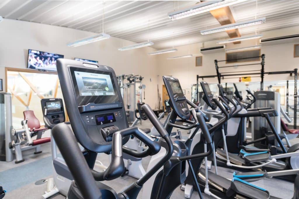 Training machines in a gym. The screen of one machine can be seen clearly in the foreground